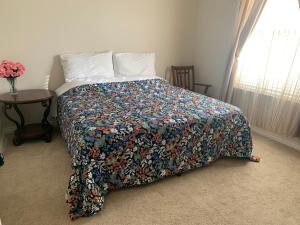 a bedroom with a bed with a floral bedspread and a table at Luxhome Rooms in Mansion in Riverside