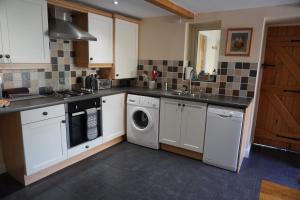 a kitchen with white cabinets and a washer and dryer at Acorn Cottage, Ashover in Ashover