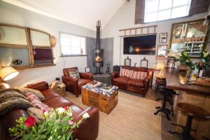 a living room with leather couches and a table at The Cowshed at Cheshire Boutique Barns in Nantwich