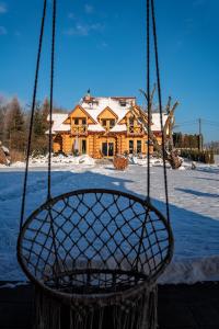 a swing in front of a house in the snow at VILLA MAZURIS in Pierkunowo