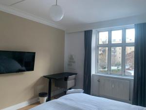 1 dormitorio con cama, ventana y escritorio en Centrally Located 4 Room Apartment en Copenhague