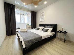 sypialnia z dużym łóżkiem i oknem w obiekcie Апартаменты LUX + w mieście Pawłodar
