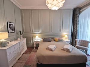 a bedroom with a large bed and a chandelier at Le Royal Couëdic - Les Maisons de Madeleine in Nantes