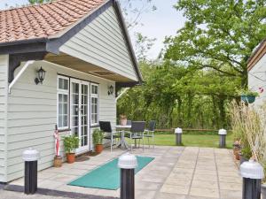 a patio with a table and chairs next to a house at Owl Lodge in Great Moulton