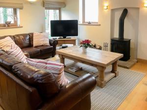 sala de estar con sofá, mesa y estufa de leña en Red House Farm Cottage en Whitegate