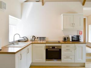 a kitchen with white cabinets and a sink at Mays Mews in binbrook