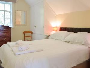 a bedroom with a white bed with towels on it at The Gate House in Pendine