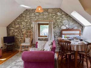 a living room with a stone wall and a table and chairs at The Granary - Hw7187 in Henrys Moat