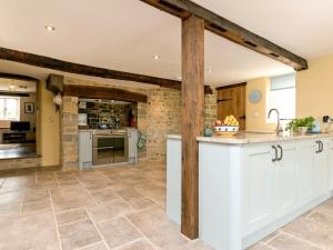 a kitchen with white cabinets and a stone wall at The Farmhouse At Higher Westwater in Axminster