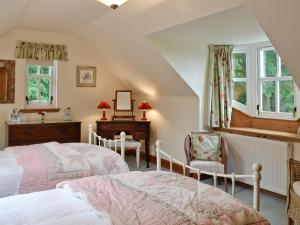 a bedroom with two beds and a desk and windows at Little Blackhall Lodge in Banchory