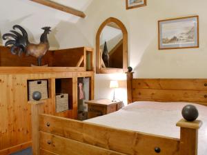 a bedroom with a wooden bed with a wooden rooster on it at The Stables in Whitland
