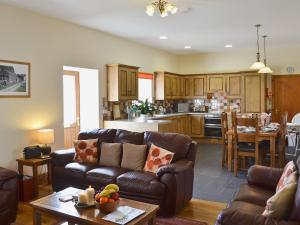 a living room with a couch and a kitchen at Eithinog in Talybont