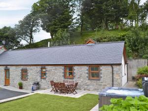 a stone cottage with a table and chairs in a yard at Eithinog in Talybont