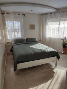 1 dormitorio con 1 cama grande en una habitación con ventanas en Chaleureux Appartement à 1 min à pied de la Mosquée Hassan II, en Casablanca