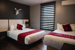 1 dormitorio con 2 camas y ventana en Auberge Beausejour, en Amqui