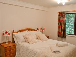 a bedroom with a bed with white sheets and a window at Long Mynd in Ambleside