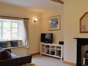 a living room with a tv and a window at Barton Cottage in North Petherwin