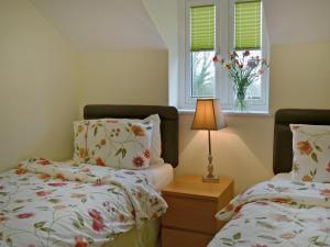 1 dormitorio con 2 camas, lámpara y ventana en Birch Lodge en Lamerton