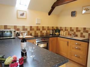 een keuken met een fles wijn en 2 glazen bij Bluebell Cottage - E4741 in Chipping Sodbury