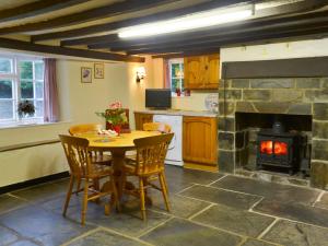a kitchen with a table and a fireplace at Gingers Cottage in Marhamchurch