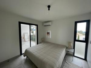 1 dormitorio con 1 cama y 2 ventanas grandes en Les Cyclistes : appartement Vintoux, en Malaucène
