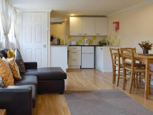 a living room and kitchen with a couch and a table at Woodlands Lodge in Rustington