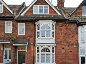 een rood bakstenen huis met witte ramen bij The Broomes in Whitstable