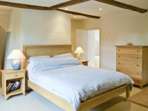 Chapel Cottage في Sharrington: غرفة نوم بسرير كبير وموقف ليلتين
