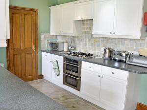 cocina con armarios blancos y fogones en Copper View, en Coniston