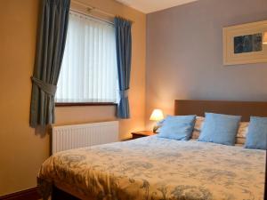 a bedroom with a bed with blue pillows and a window at Copper View in Coniston