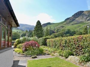 un jardín frente a una casa con montañas en el fondo en Copper View, en Coniston