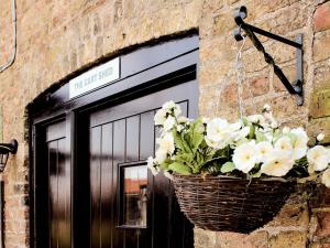 a basket of white flowers hanging on a building at The Cart Shed in Tickton