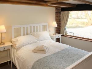 a bedroom with a white bed with two lamps and a window at The Cart Shed in Tickton