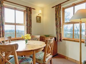 a dining room with a table and chairs and windows at Moy in Taynish