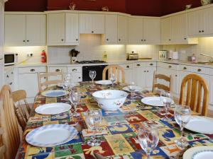 a kitchen with a table with plates and wine glasses at Maes Gwyn - Hw7644 in Llandudno