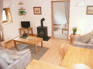 a living room with a couch and a wood stove at Garden Lodge in Llanvair Waterdine