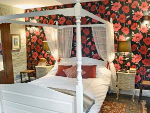 WeareにあるRagwood Cottageの花柄の壁紙を用いた白い天蓋付きベッドが備わるベッドルーム1室