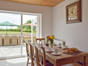 a dining room with a table and a clock on the wall at The Sycamores in Clynderwen