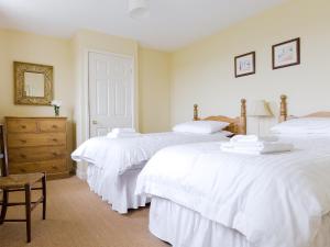 a bedroom with two white beds and a chair at Levisham in Pickering