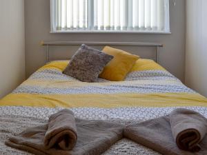 uma cama com um cobertor e almofadas em Ashover Lodge em Kinmel Bay