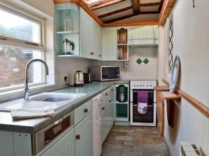 a kitchen with white cabinets and a sink at The Old Thatch in Christchurch
