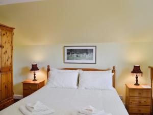 a bedroom with a white bed with two night stands at Kennedy Cottage in Straiton