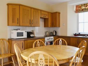 a kitchen with a table and chairs and a microwave at Kennedy Cottage in Straiton