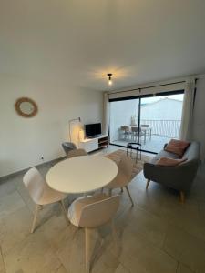 sala de estar con mesa blanca y sillas en Les Cyclistes : appartement Vintoux, en Malaucène