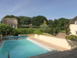 a swimming pool in front of a house at Monks Thatch in Otterton