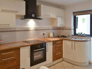 a kitchen with white cabinets and a stove top oven at Ty Haf in Trearddur