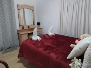 Un dormitorio con una cama roja con dos animales de peluche. en Enjoy home en Jerusalem