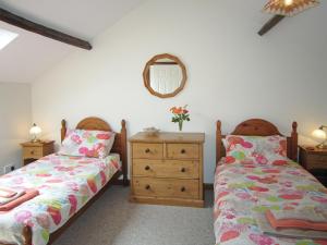 a bedroom with two beds and a dresser and a mirror at Valley View- Hms in Combe Martin