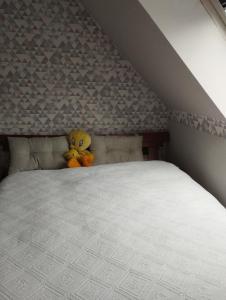 a yellow teddy bear sitting on top of a bed at Le jardin aux oiseaux in Saint-Jouan-de-lʼIsle