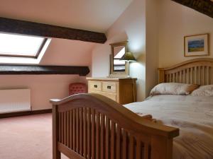 ホークスヘッドにあるTarns Cottageのベッドルーム(木製ベッド1台、鏡付)